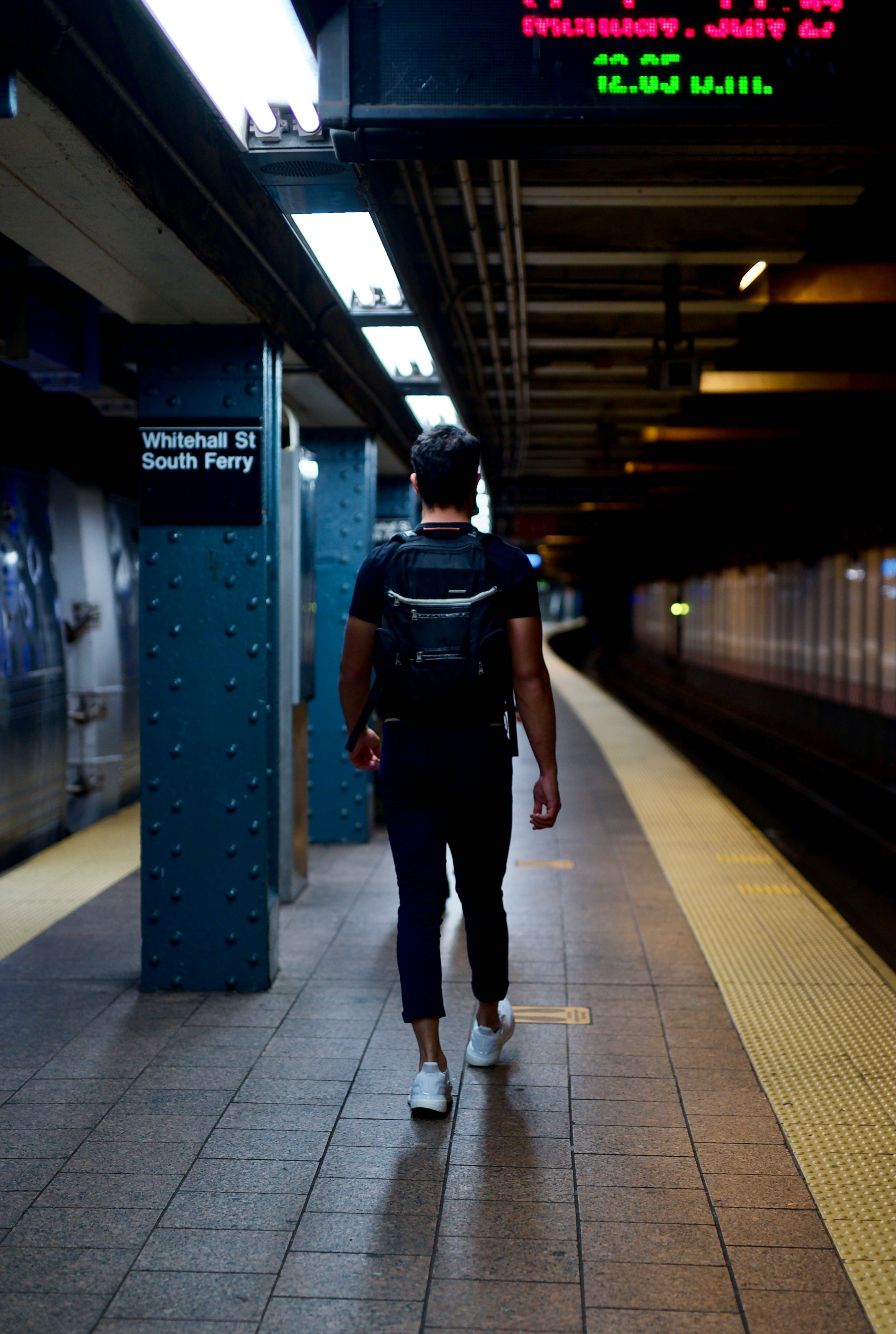 man in black jacket and black pants walking on train station